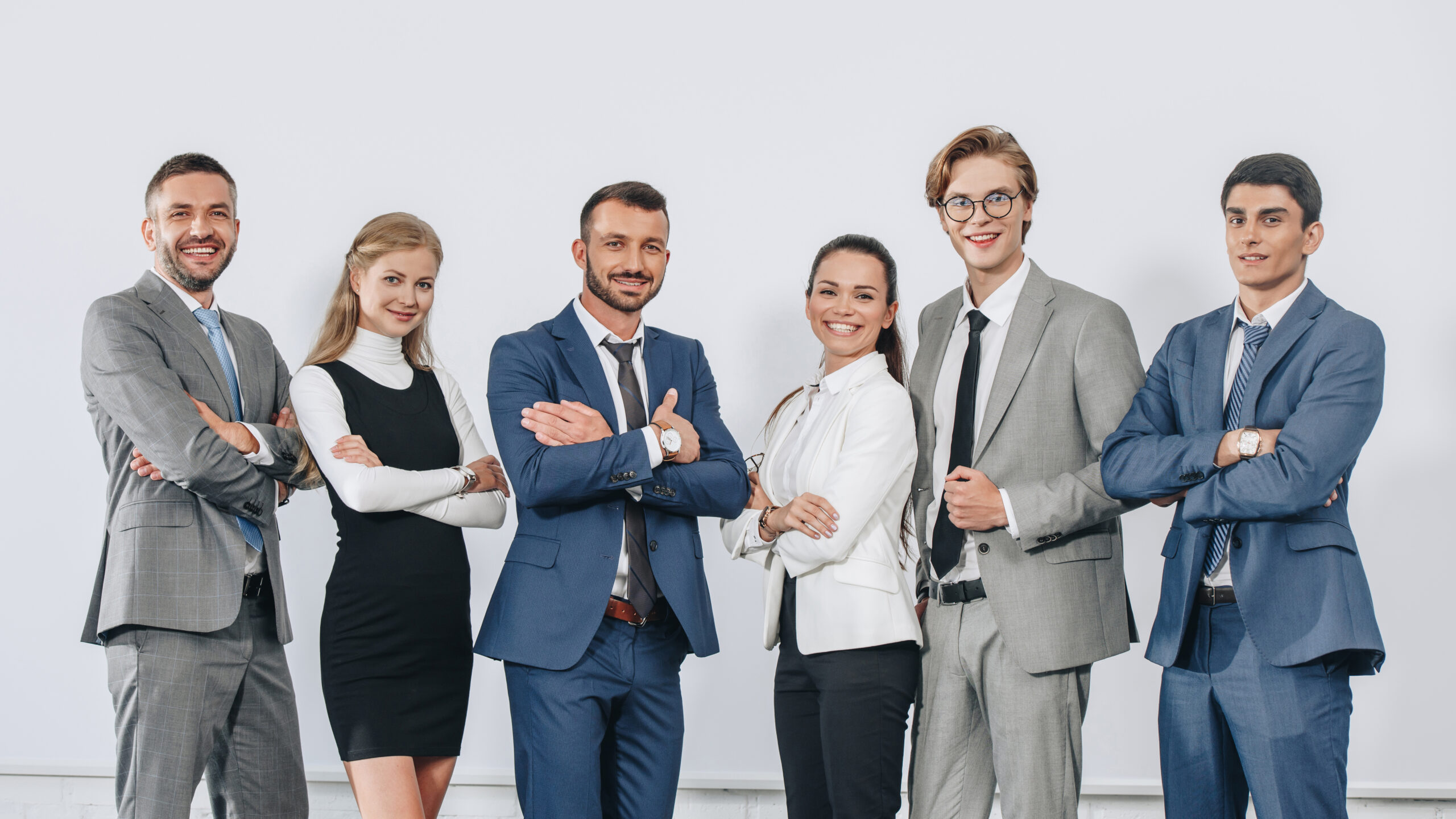 smiling businesspeople with crossed arms posing near board after training in hub and looking at